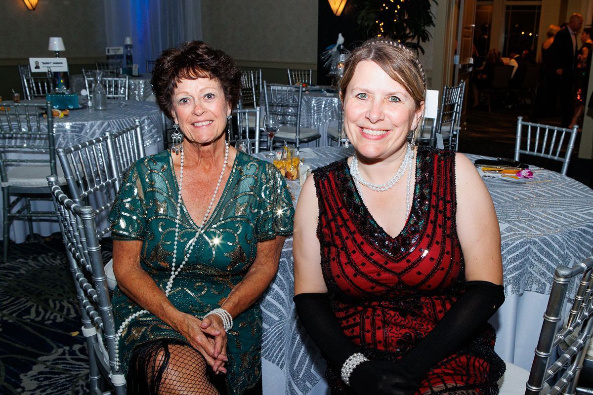 Two women are sitting at a table and smiling for the camera.