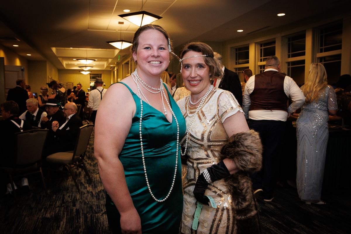 Two women in dresses are posing for a picture in a room.