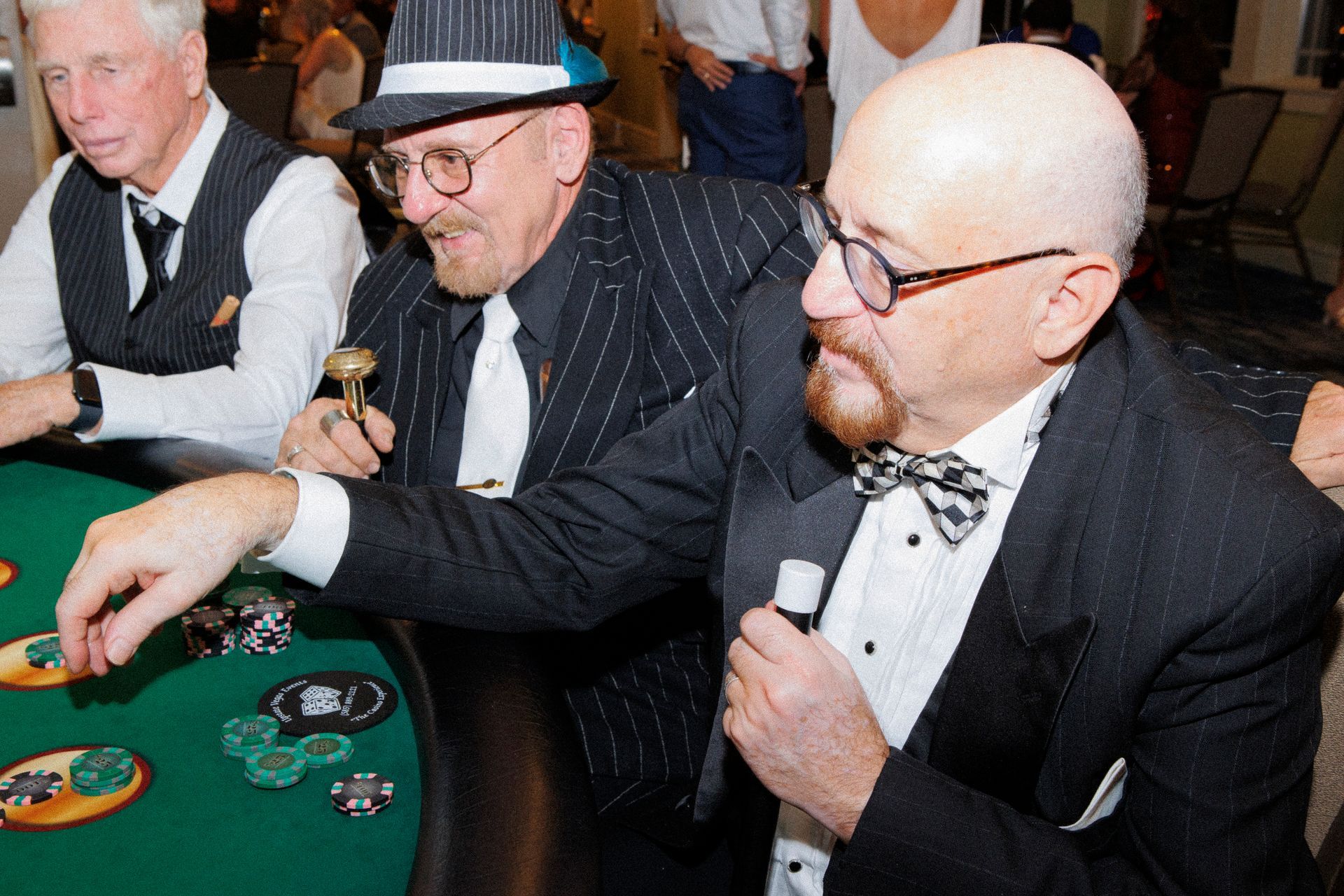 Three men in suits and hats are playing poker at a table.