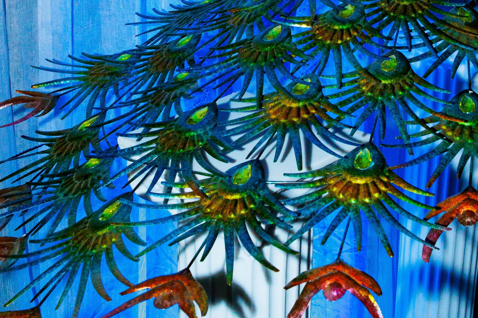 A close up of a painting of peacock feathers on a blue background.