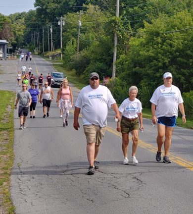 A group of people are walking down a road wearing shirts that say ' volunteer ' on them
