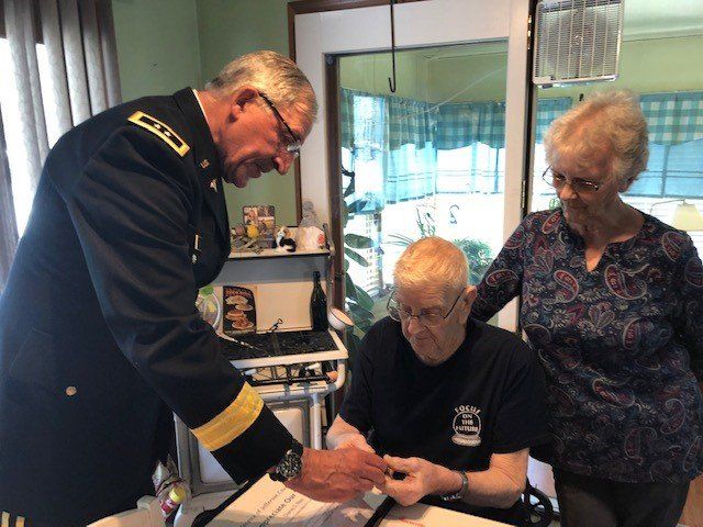 A man in a military uniform is talking to a man in a wheelchair