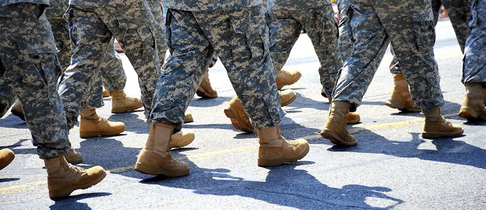 Soldiers in camouflage uniforms marching in formation. Brown boots are visible.
