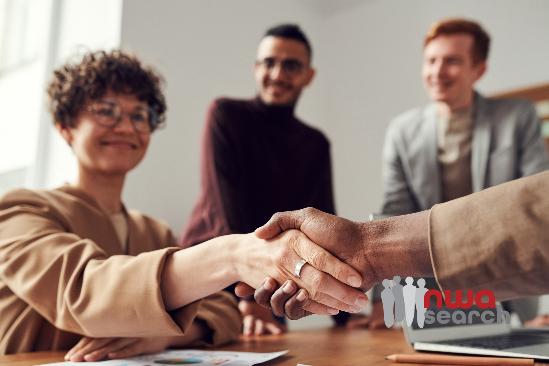 A group of people are shaking hands at a table.