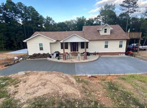 A large white house with a concrete driveway in front of it.
