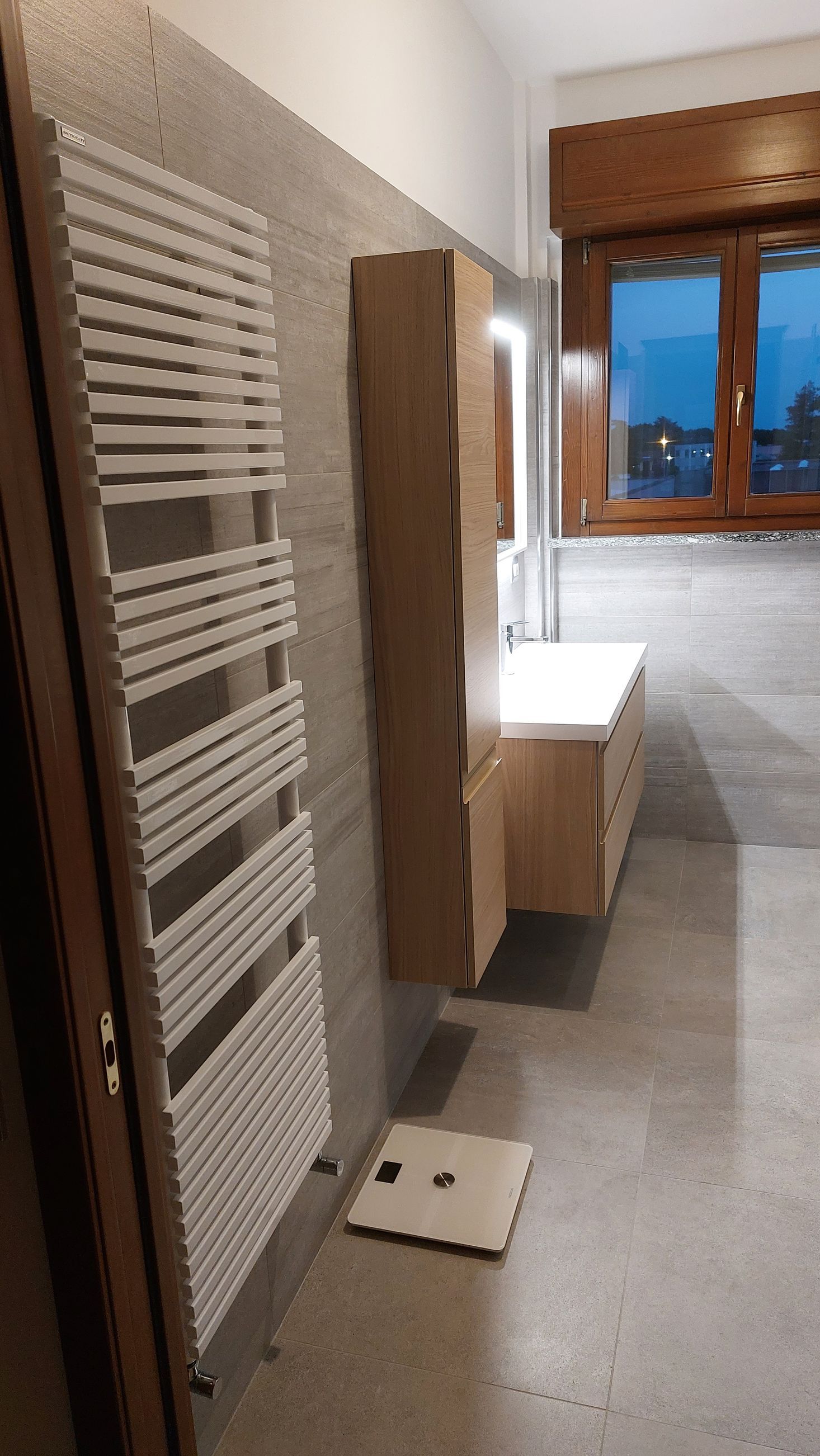 Un bagno con portasciugamani e bilancia sul pavimento.