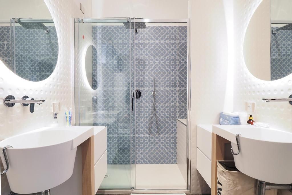 Un bagno con due lavandini, una doccia e due specchi.