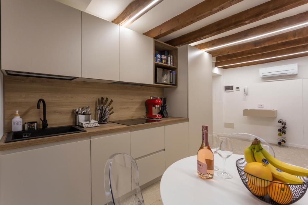 Una cucina con una bottiglia di vino e una ciotola di frutta su un tavolo.