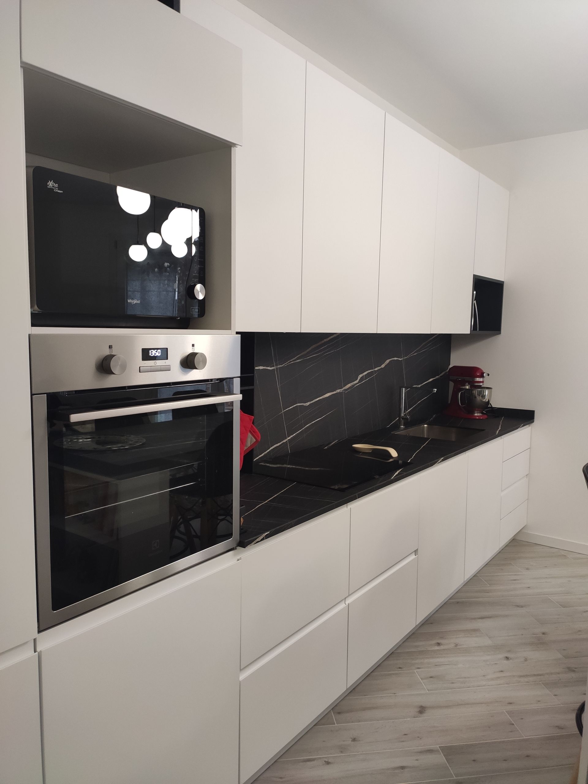 Una cucina con mobili bianchi e ripiani neri