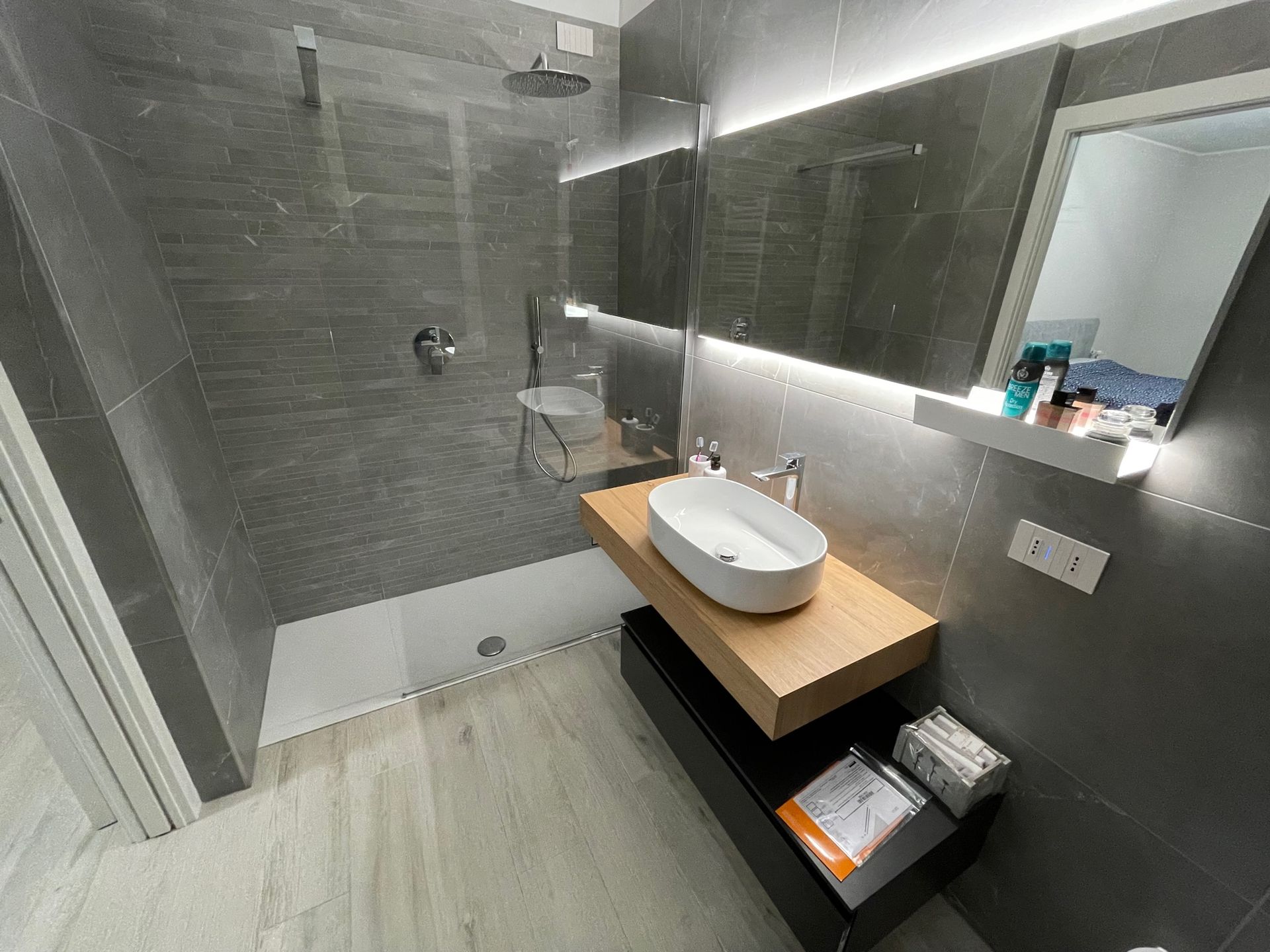 Un bagno con lavandino, specchio e doccia.