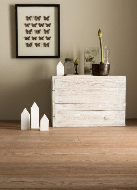 Un quadro di farfalle è appeso sopra una cassettiera bianca