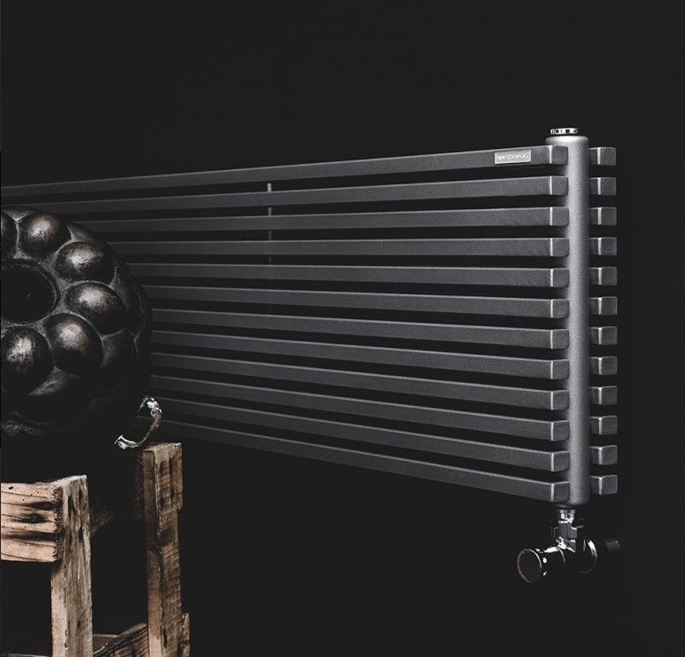 Un radiatore nero è appoggiato su uno sgabello di legno.