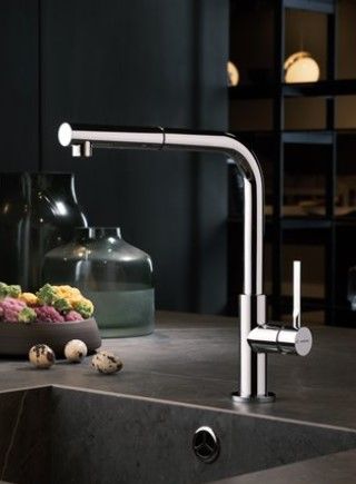 Un lavello da cucina con un rubinetto e una ciotola di verdure sul tavolo.