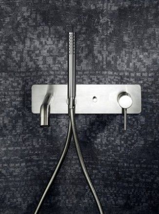 Un soffione doccia in acciaio inossidabile è appeso a una parete.