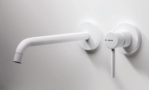 Un rubinetto per lavandino bianco montato a parete con una maniglia su una parete bianca.