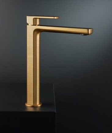 Un rubinetto dorato è appoggiato su un piano di lavoro nero