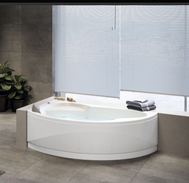 Una vasca da bagno in un bagno accanto a una finestra con le persiane