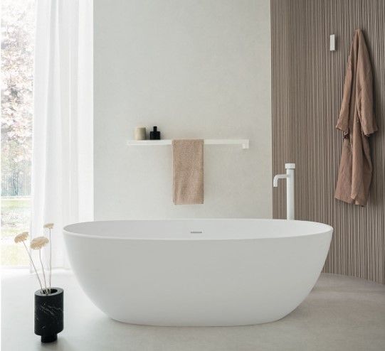 Una vasca da bagno bianca si trova in un bagno accanto a una finestra.