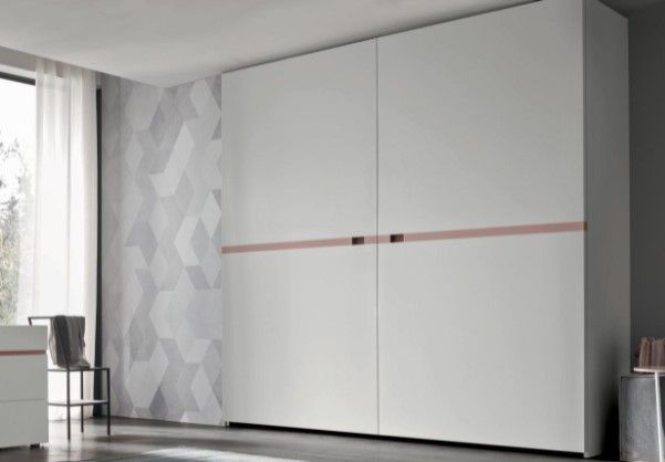Un grande armadio bianco con ante scorrevoli in una camera da letto