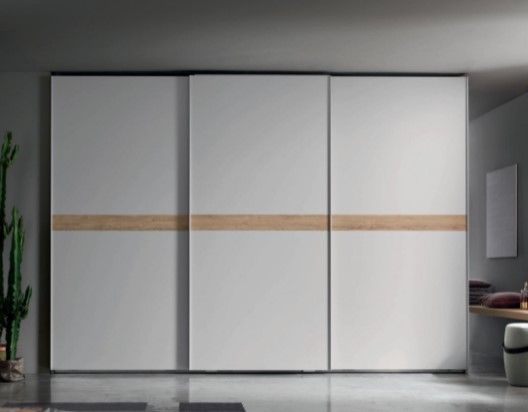 Un grande armadio bianco con ante scorrevoli in una stanza