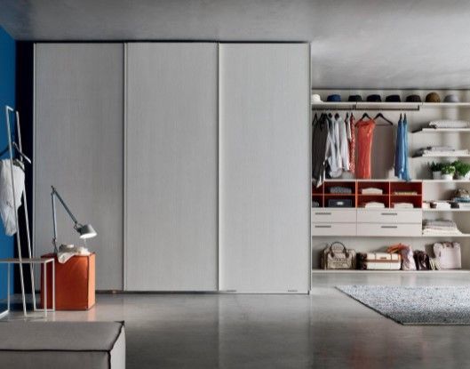 Un armadio con ante scorrevoli e ripiani pieni di vestiti
