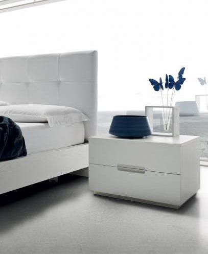 Una camera da letto con un letto e un comodino con sopra un vaso di fiori.