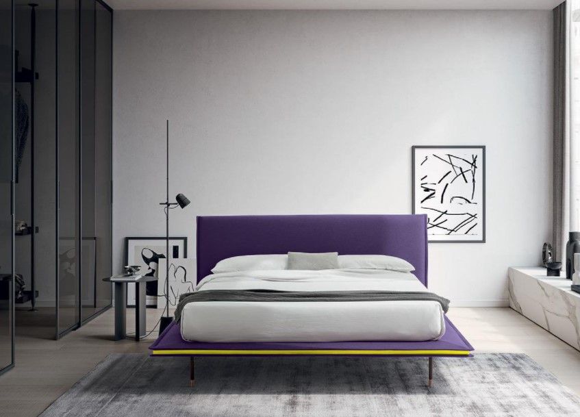 Una camera da letto con un letto viola e una testiera viola.