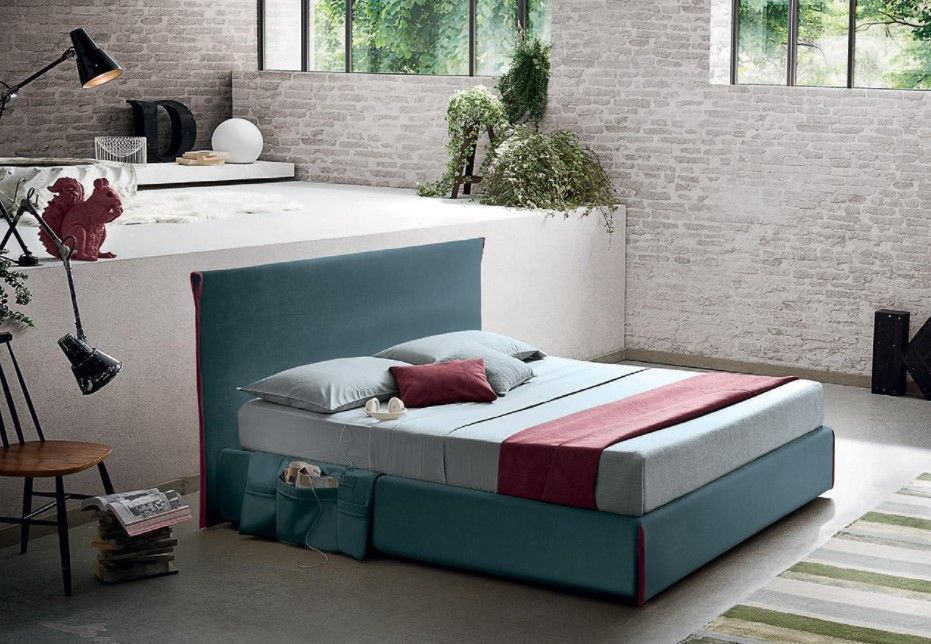 Un letto con la testiera blu si trova in una stanza con un muro di mattoni.