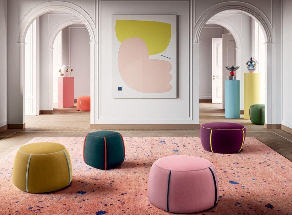 Un gruppo di pouf colorati è appoggiato su un tappeto in una stanza.