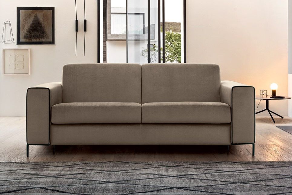 Un divano è posizionato in un soggiorno accanto a una finestra.