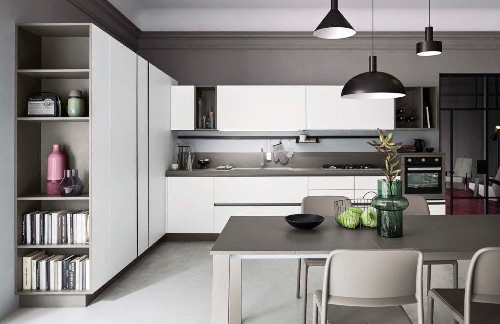 Una cucina con mobili bianchi, tavolo e sedie