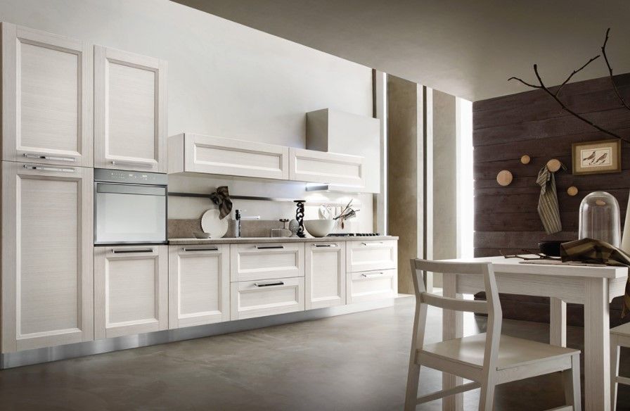 Una cucina con mobili bianchi, tavolo e sedie