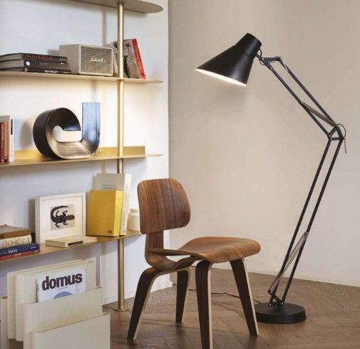 Una stanza con una sedia, una lampada e uno scaffale con una rivista chiamata domus sopra
