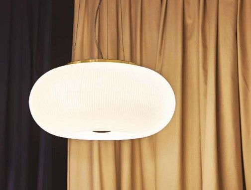 Una lampada a sospensione bianca è appesa al soffitto davanti a una tenda.