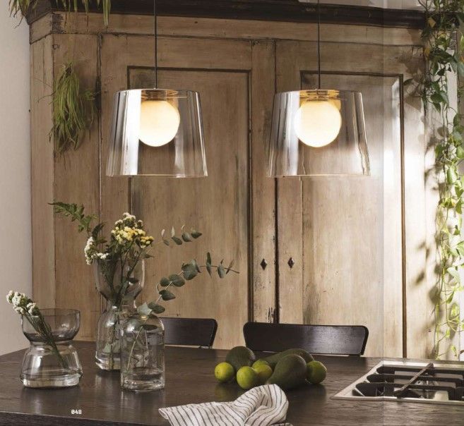 Una cucina con due lampade a sospensione in vetro trasparente appese al soffitto