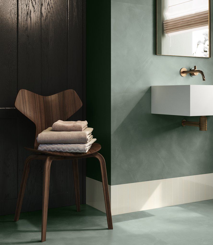 Una sedia di legno con sopra una pila di asciugamani in un bagno accanto a un lavandino.