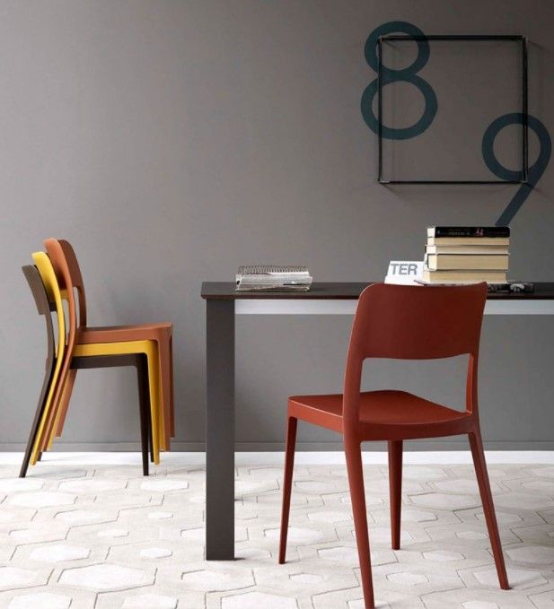 Una pila di sedie è posta accanto a un tavolo con sopra dei libri
