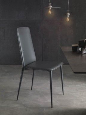 Una sedia nera è appoggiata accanto a un tavolo in una stanza.