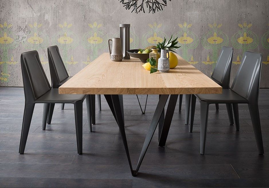 Un tavolo da pranzo con sedie e un vaso di frutta sopra.