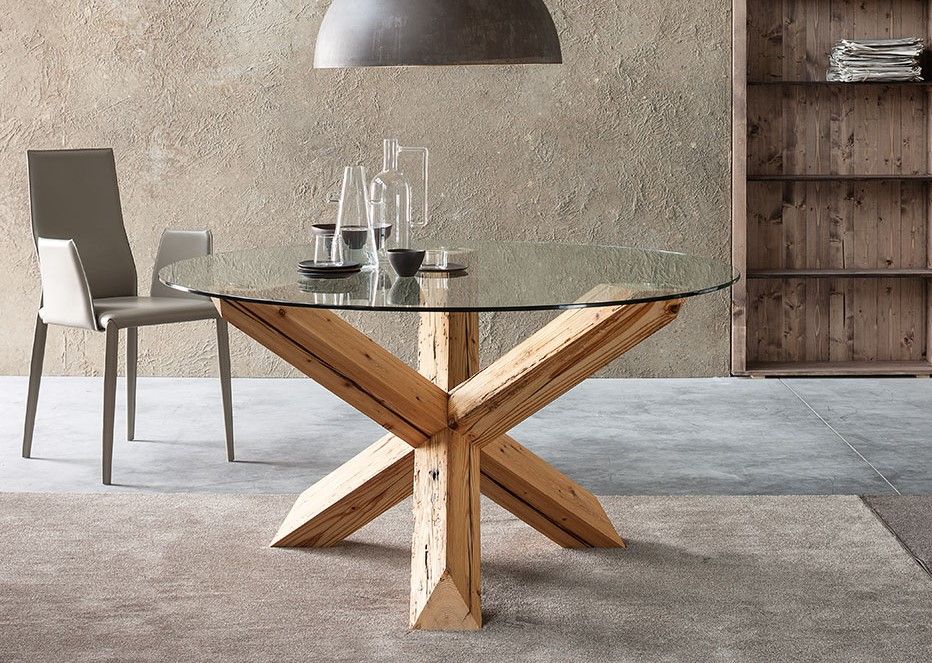 Un tavolo da pranzo con piano in vetro e base in legno