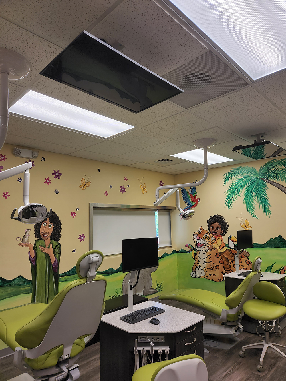 Hillside Family Dentistry patient chairs with colorful collage all over the walls with tv screens on the ceiling