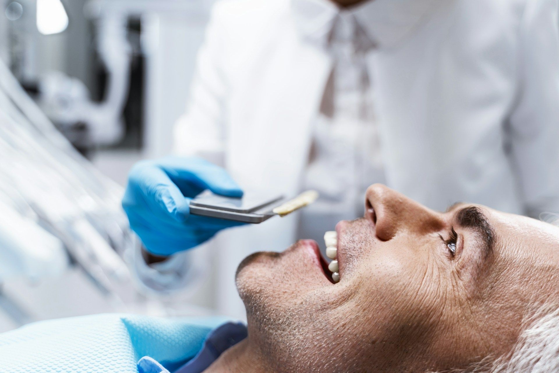 A man is laying in a dental chair while a dentist examines his teeth.