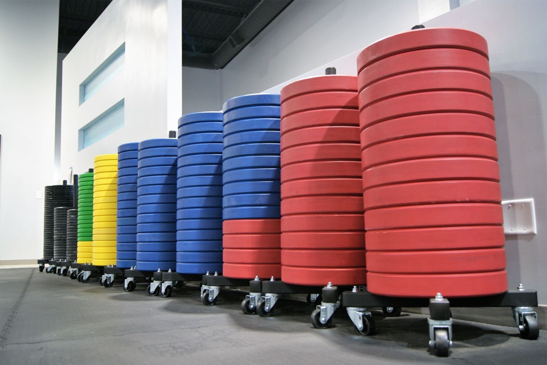 A row of colorful weight plates on wheels in a gym