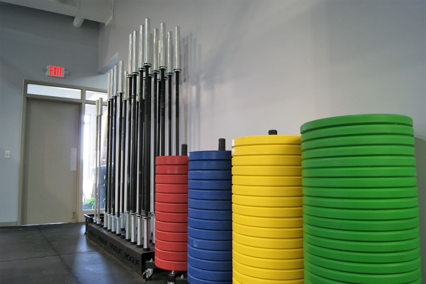 A bunch of colorful weights are stacked on top of each other in a gym.