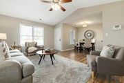 Bright living room with gray sofa, armchairs, coffee table, and dining area in the background