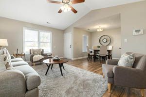Bright living room with gray sofa, armchairs, coffee table, and dining area in the background