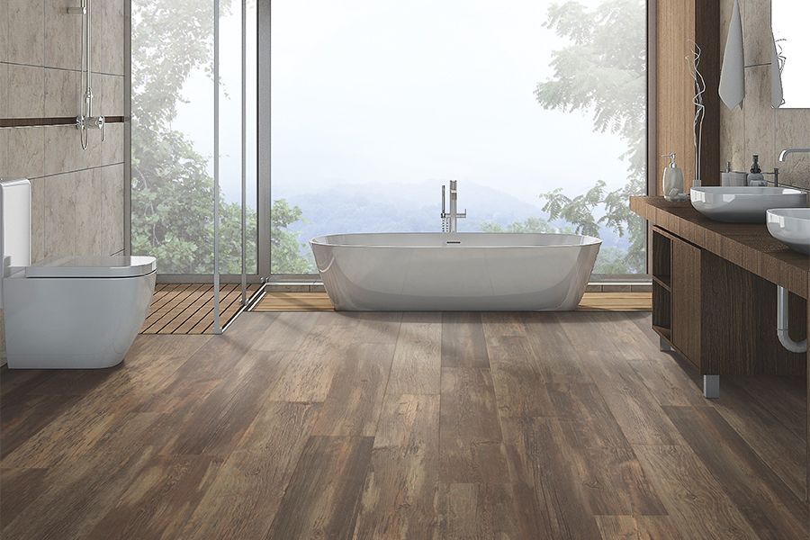 Modern bathroom with a freestanding tub, wood floor, and large windows overlooking a misty view