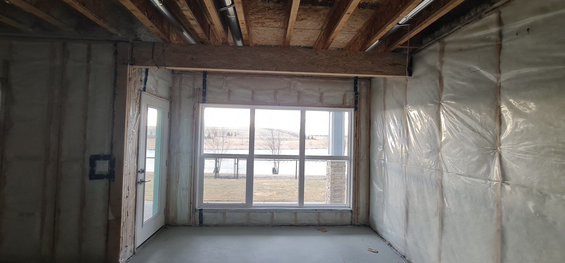 picture showing before state of an unfinished basement with a window overlooking a pond