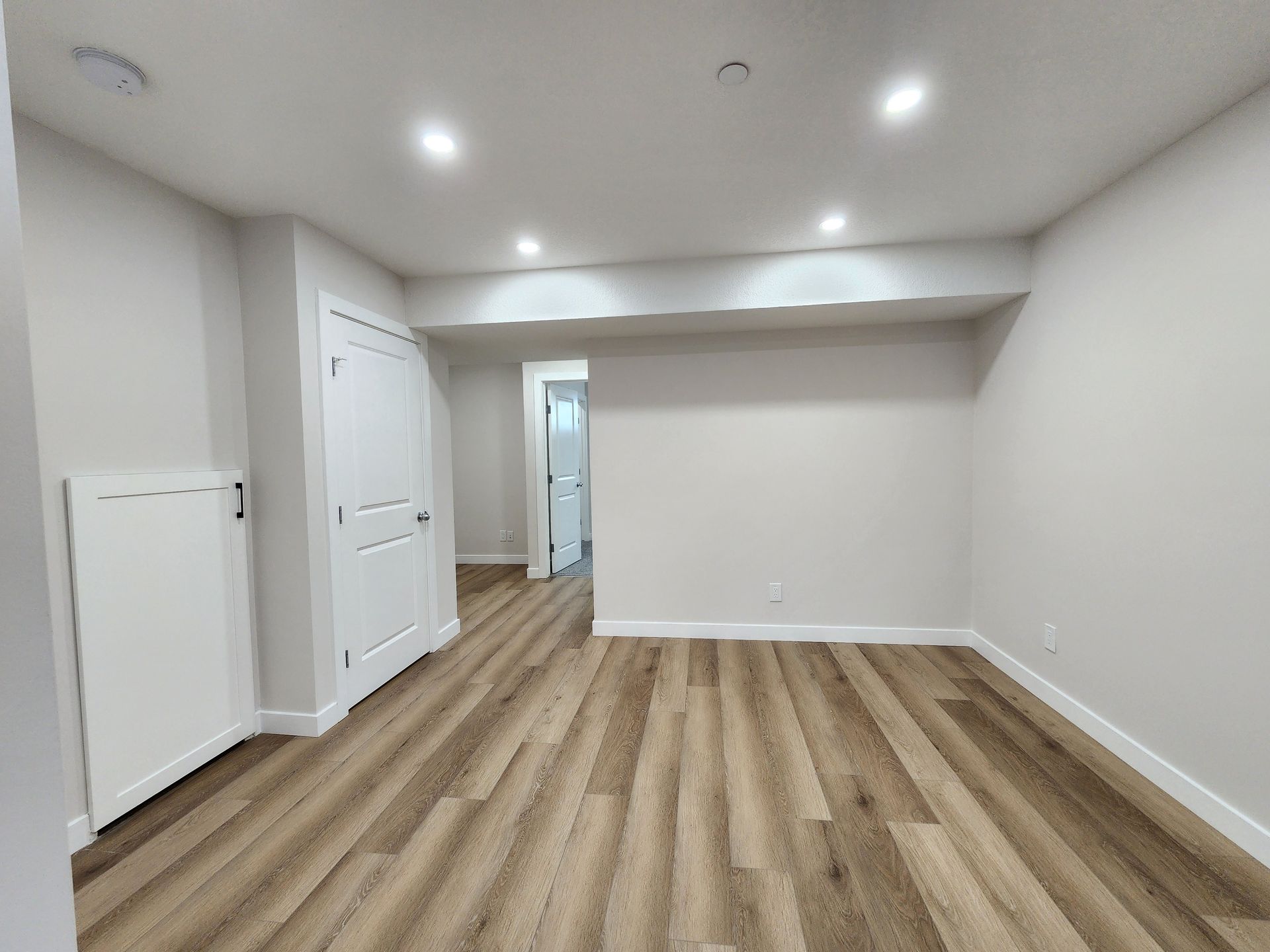 Spacious and well-lit basement room with Vinyl flooring and multiple doorways in a Calgary home.