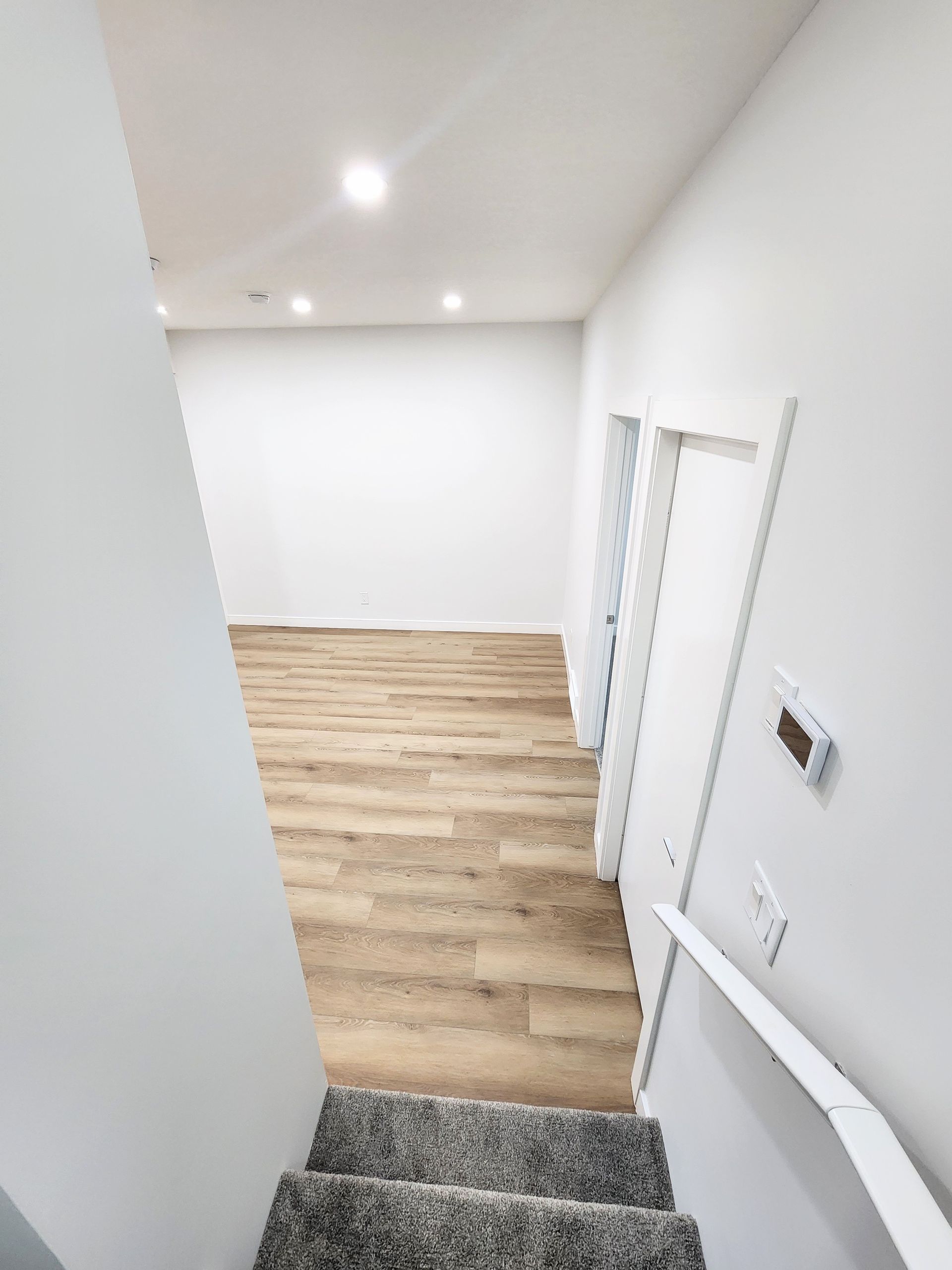 Staircase leading to a bright, spacious basement with wood flooring and white walls in a Calgary house